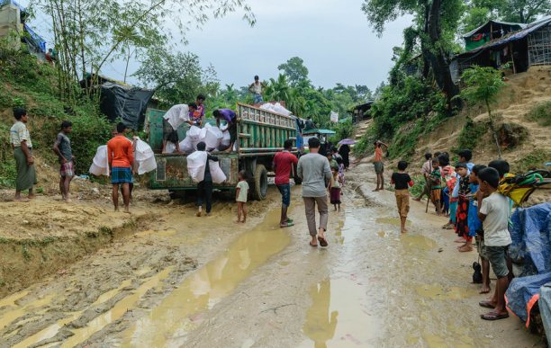 People in the street next to a truck with materials.