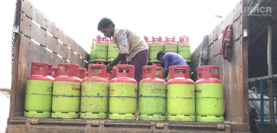 Man in middle of gas containers on top of a truck.