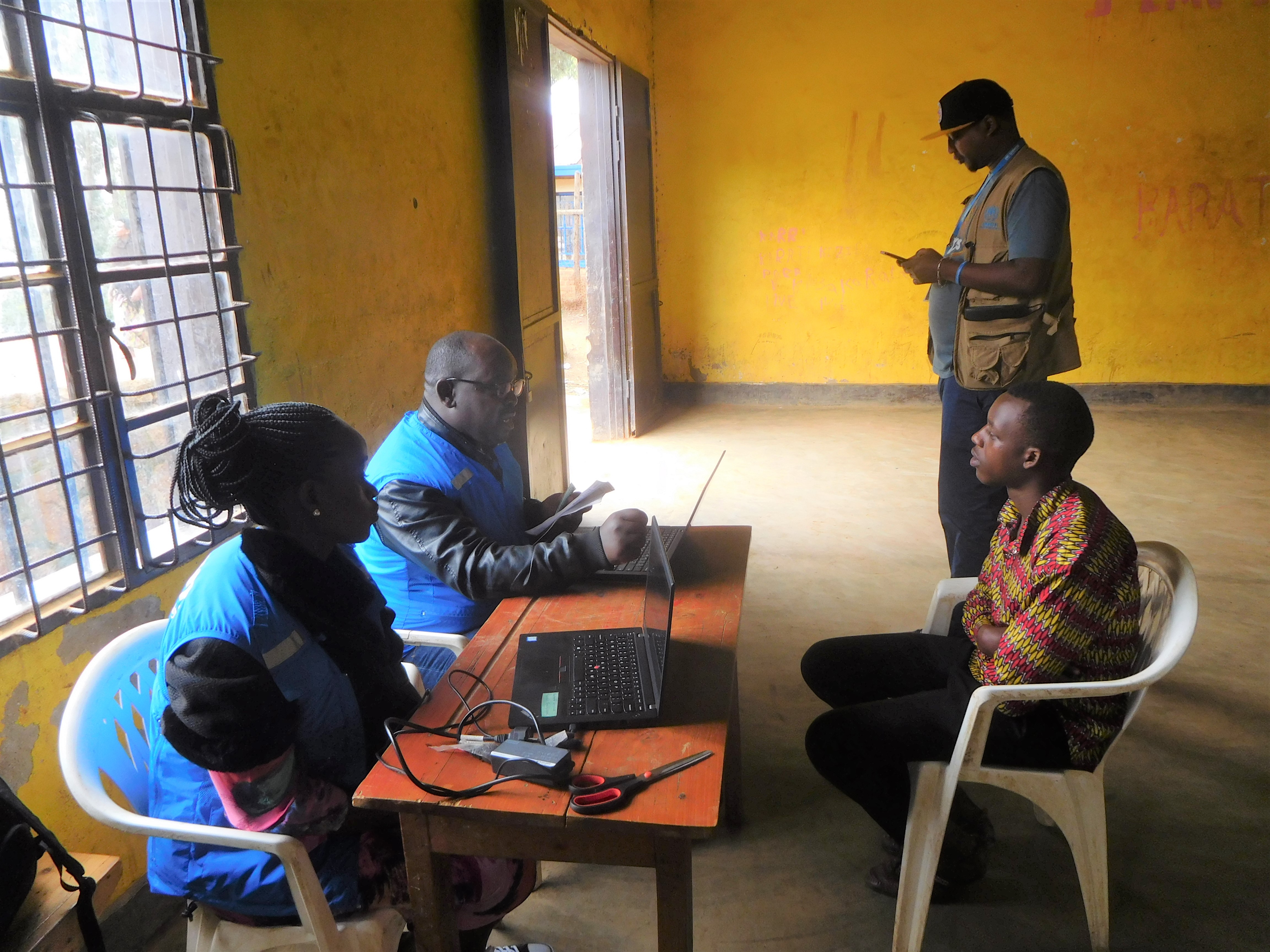 Man sitting in front of two UNHCR staff separated by a table.