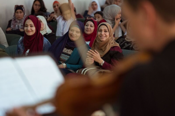 In the foreground a blurry violinist, in the background women smiling