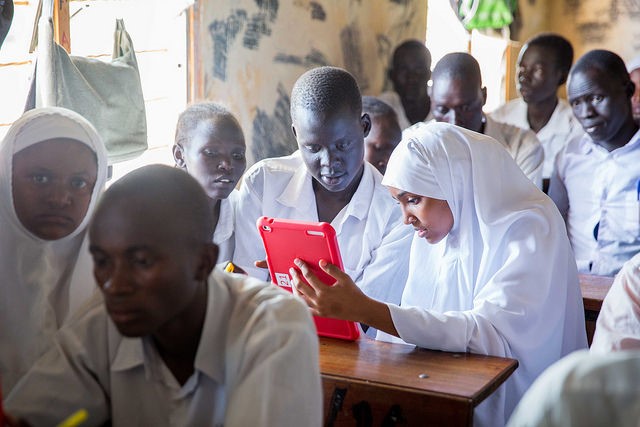 Students in a grassroom look at a tablet