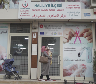 Woman walking past a Sexual and reproductive health centre with a baby. 