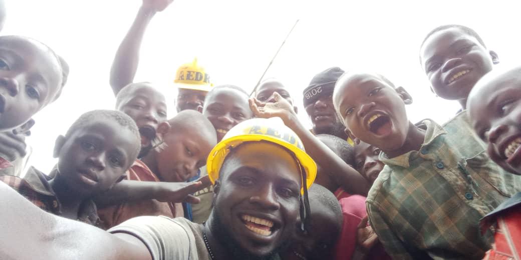 Workers with AEDR helmets pose with children from the camps