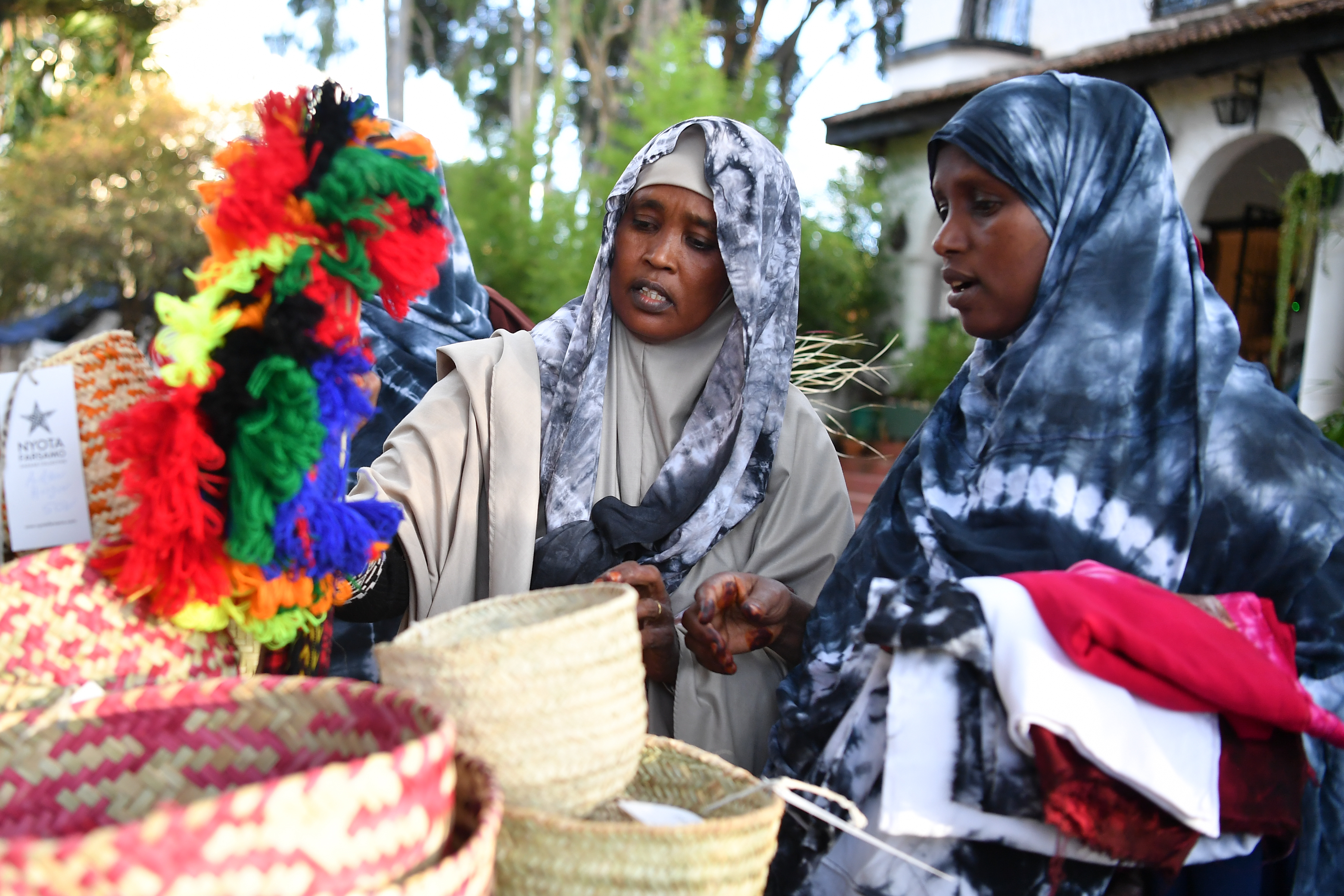 Two ladies look at goods on a market stall