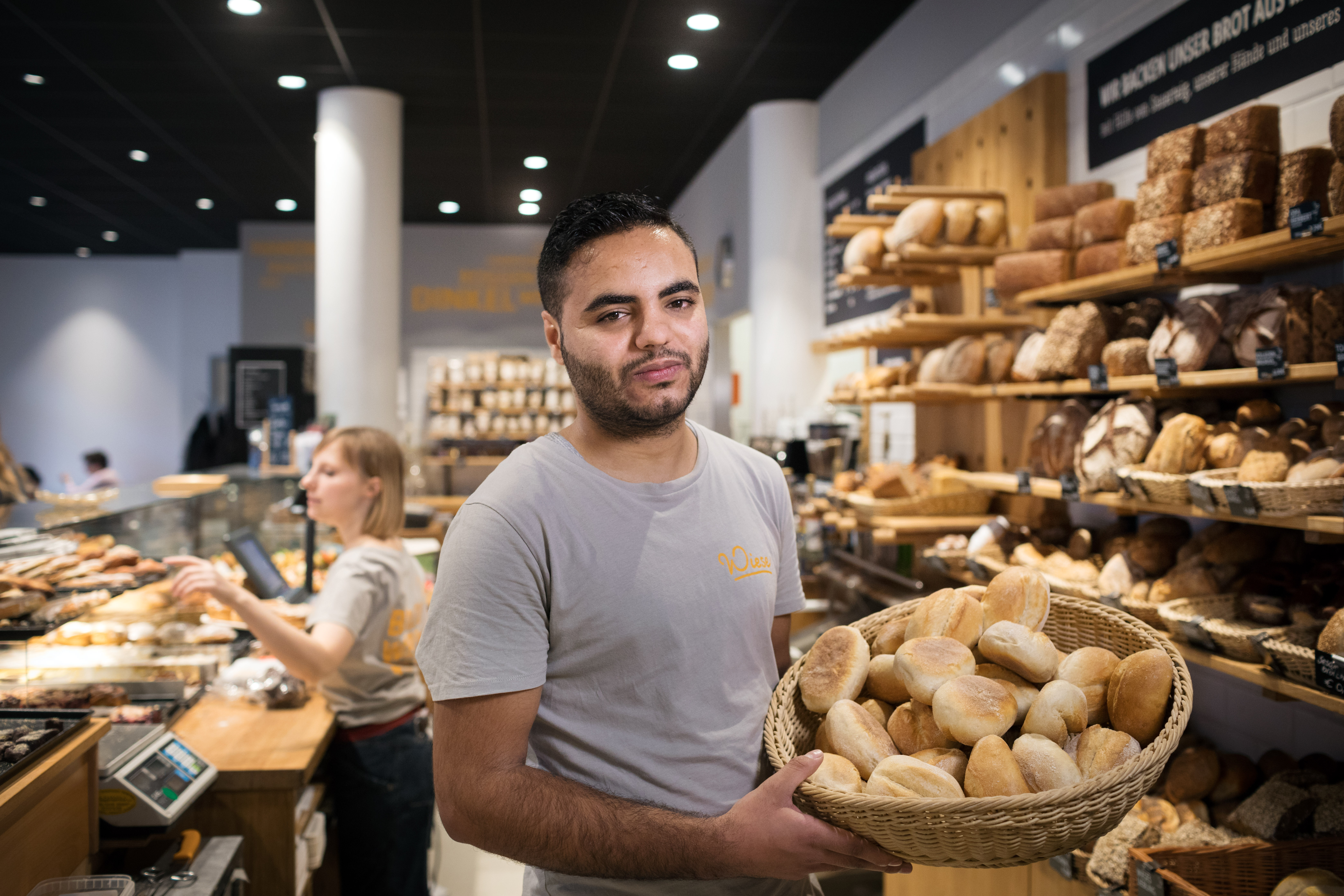 A man in a bakery displays a basket of bread.