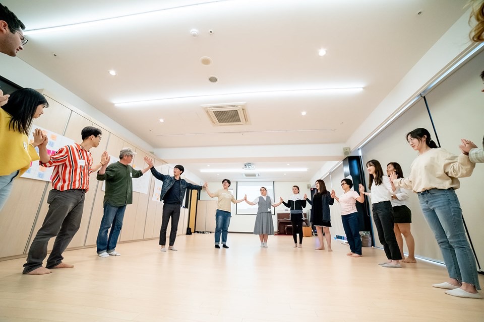 People touching hands in a circle in a room.