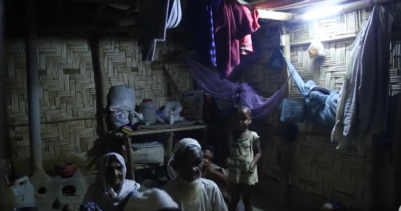 Family at a household in a camp setting, with light turned on.