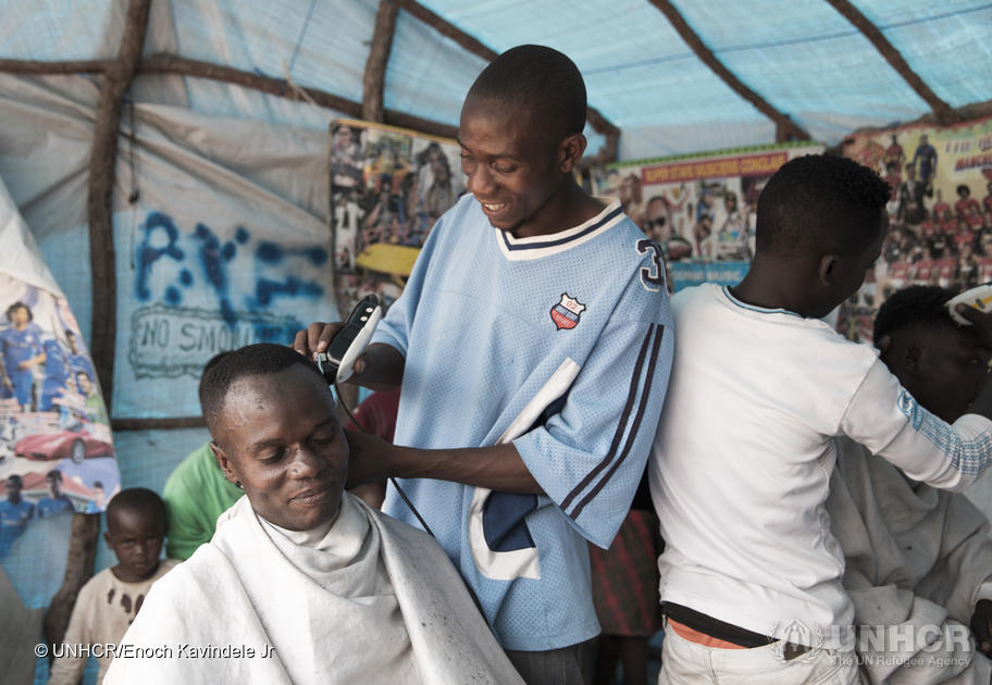 A man is giving another man a haircut at his barbershop