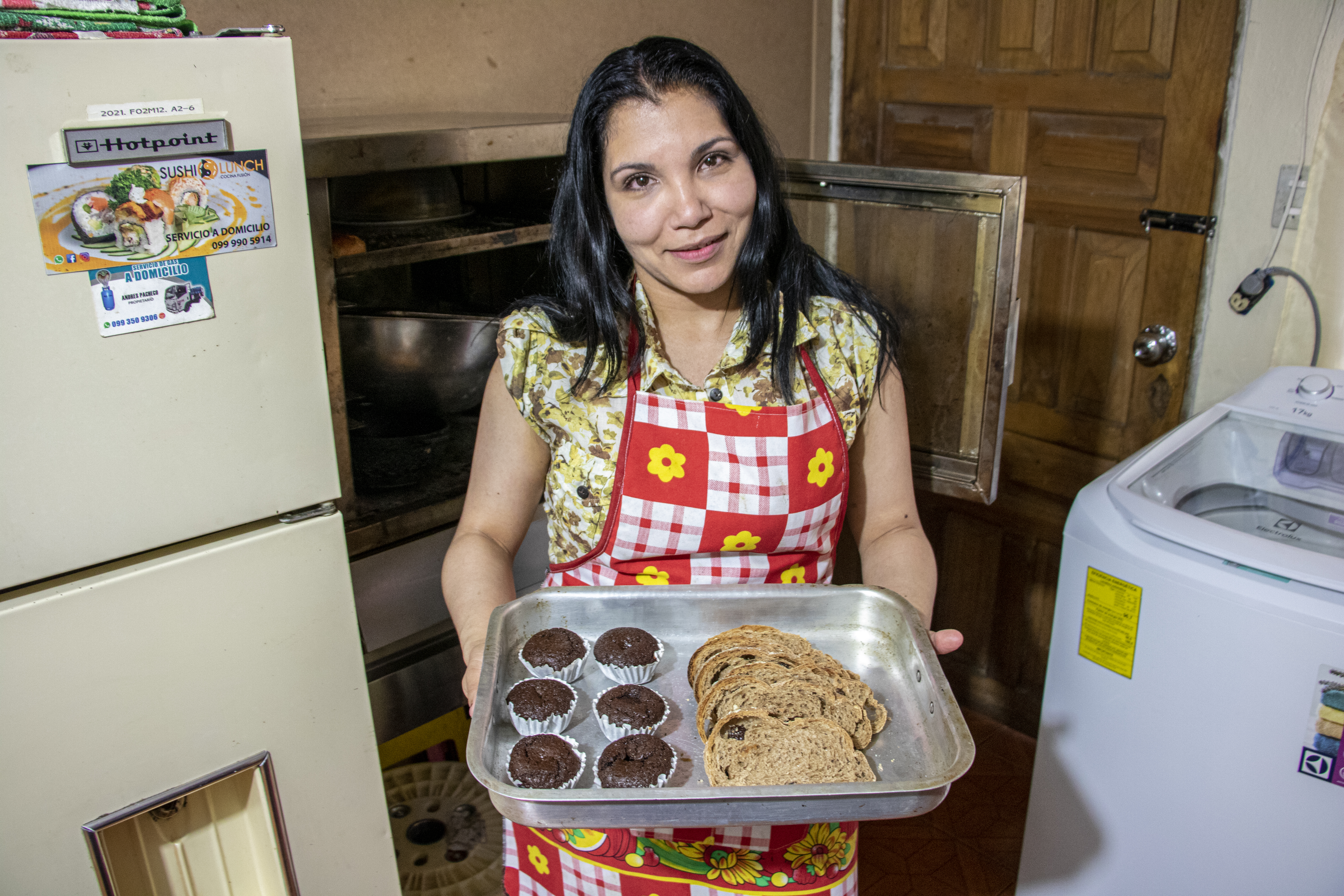 A lady shows a tray of baked goods