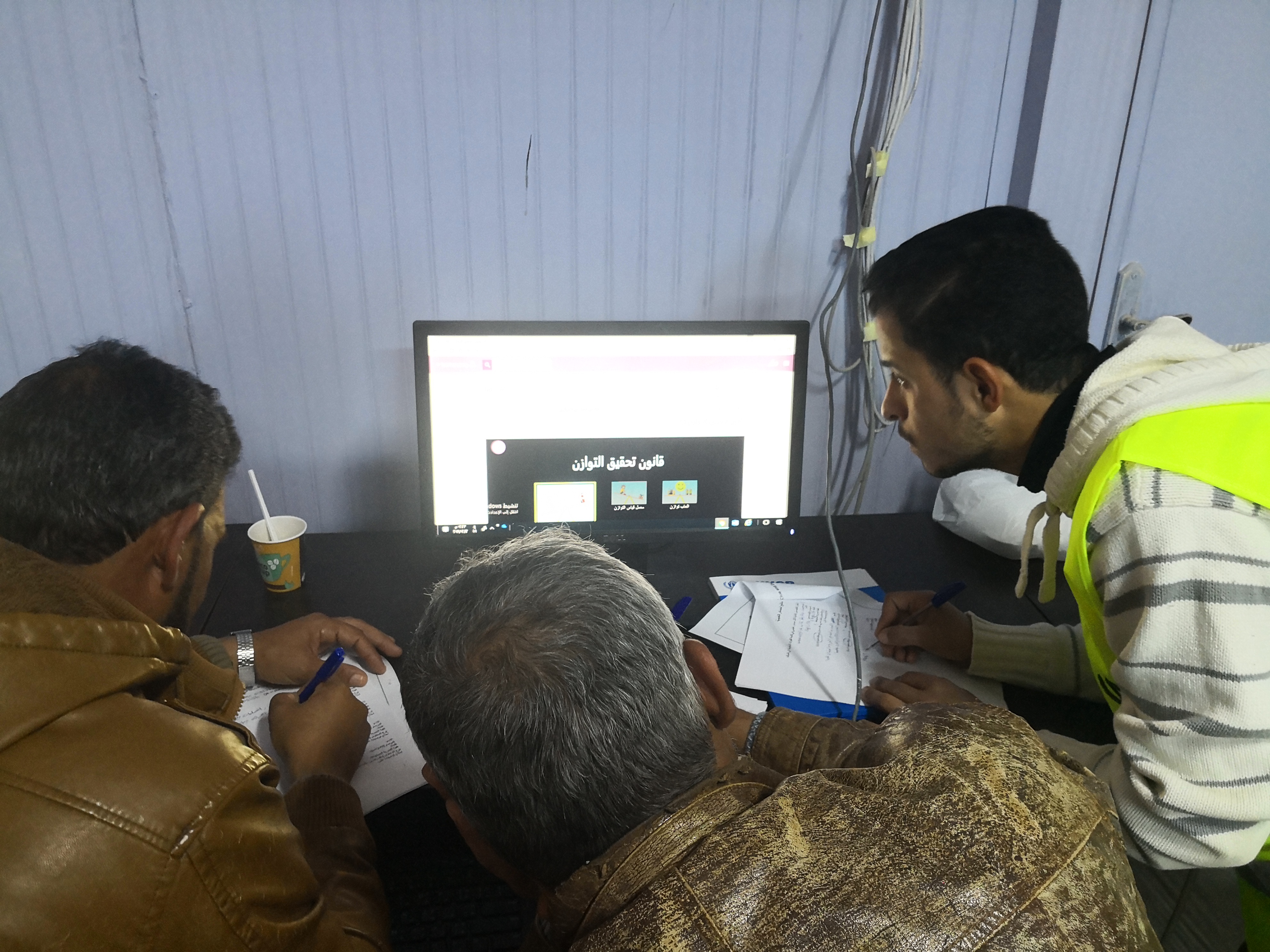 Refugees in front of computer using the education platform
