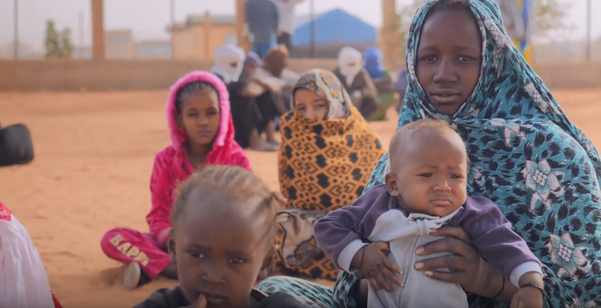 A woman and children seating in the ground.