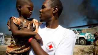 Humanitarian worker with refugee child on his arm