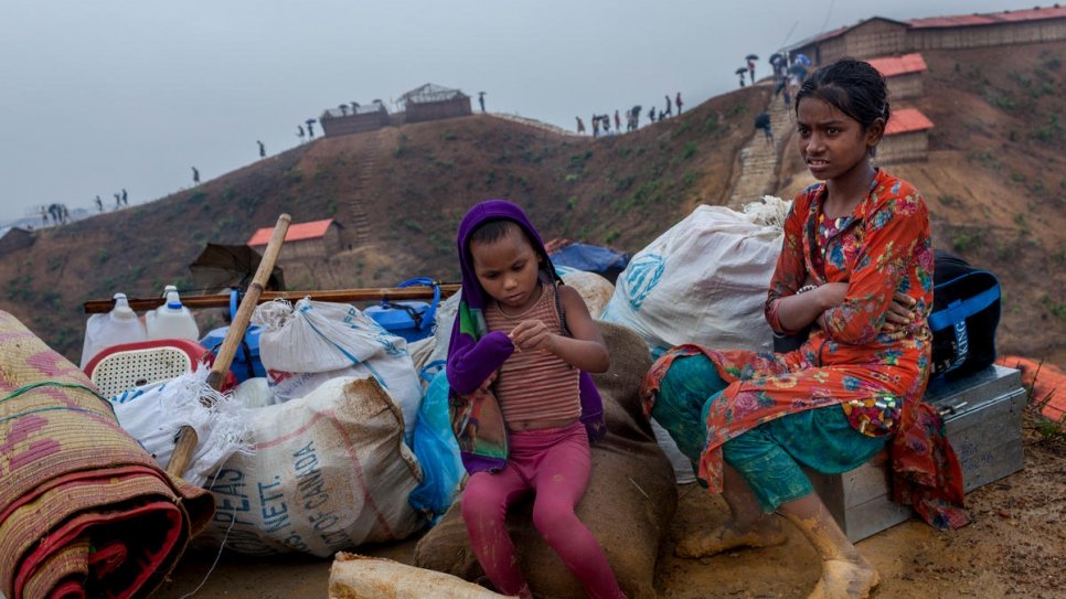 Rohingya refugees Bibi, 4, and Jannatul, 11, sit with their belongings as they wait to move into a new shelter at Camp 4, Kutupalong. Their family's previous home was destroyed by a landslide.