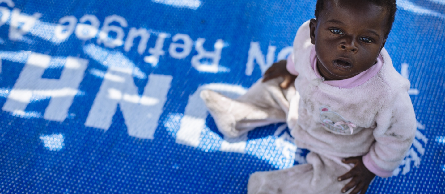 Six-month-old South Sudanese refugee Emma sits on a mat in the shade in Bidibidi refugee settlement, Yumbe District, Northern Region, Uganda.