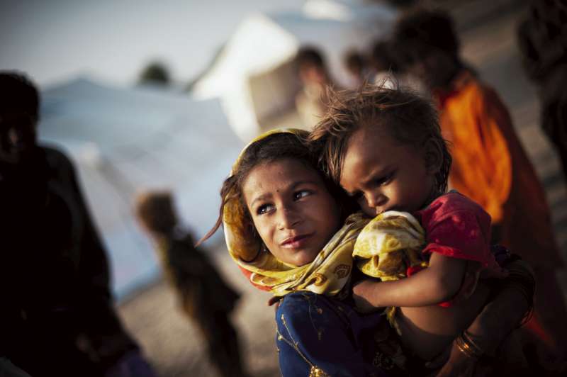 هوري تلو البالغة من العمر ثماني سنوات تحمل ابنة أخيها فيجي التي تبلغ من العمر 18 شهرًا في مخيم للإغاثة الطارئة للسكان المنكوبين من الفيضانات في إقليم سانغهار في إقليم السند الجنوبي.