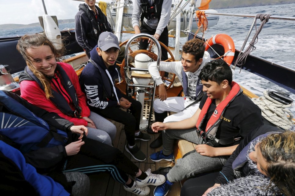 أطفال في سن المراهقة من سوريا وإيرلندا يتعلمون الإبحار معاً قبالة ساحل غرب كورك، إيرلندا. يتعلم هؤلاء الأطفال والذين يعيشون جميعاً في بالاغاديرين، في مقاطعة روسكومون، مهارات الإبحار بالإضافة إلى العمل الجماعي.