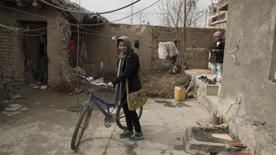 Twenty-seven-year-old Afghan returnee Kobra Yusufy checks her bicycle before leaving for class in Kabul, Afghanistan.