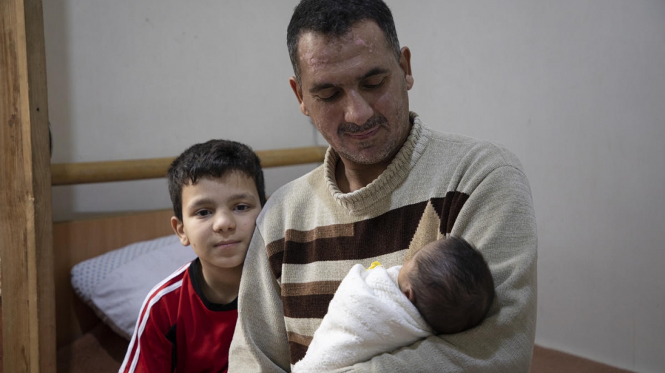 Formerly displaced father Rabih, 45, holds his newborn baby, Mustafa, at their home in Aleppo, Syria.