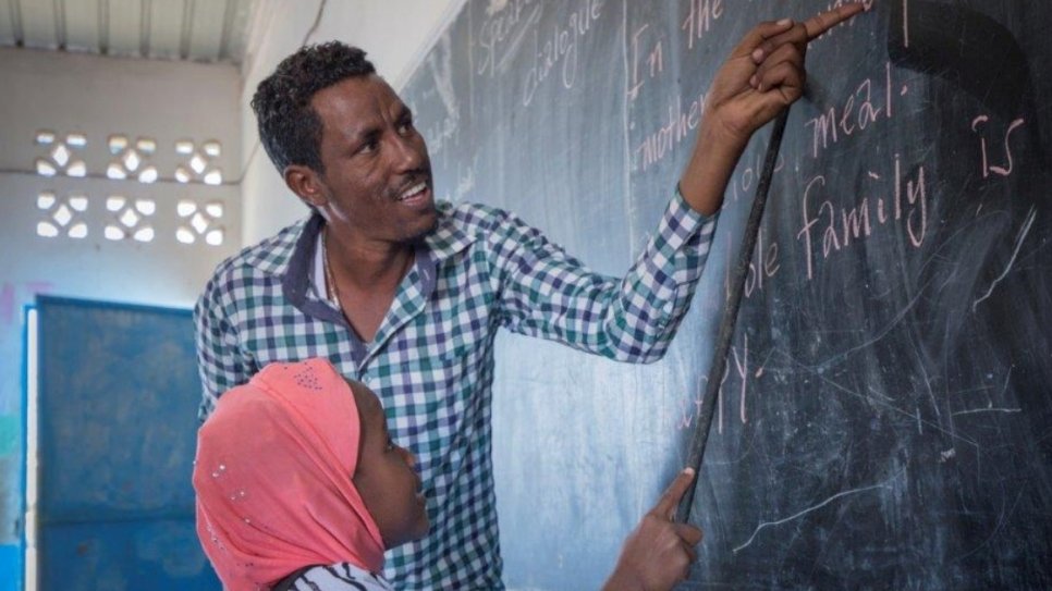 A teacher and his student in front of a black board.