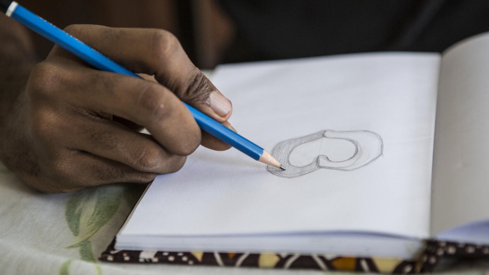 Ivorian graphic designer O'Plérou sketches the design of the World Refugee Day 2020 emoji on paper before he moves to the computer. 