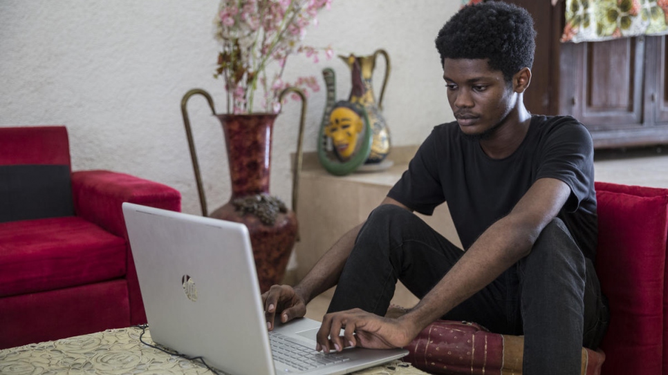 Ivorian graphic designer O'Plérou works on the World Refugee Day 2020 emoji on his computer.