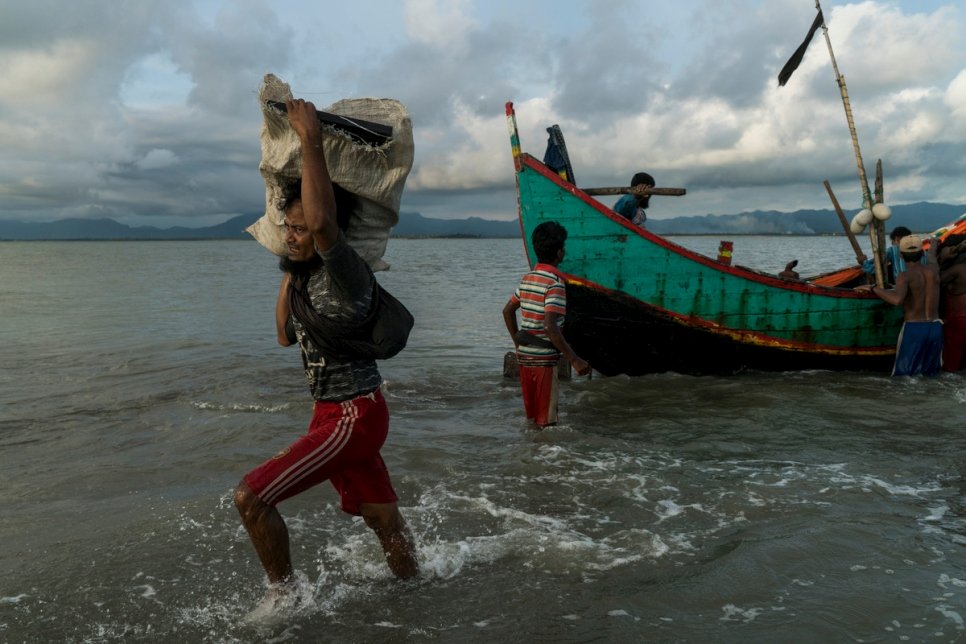 رجل من الروهينغا يحمل حزمة ويتجه إلى الشاطئ في داخينبارا، بنغلاديش.