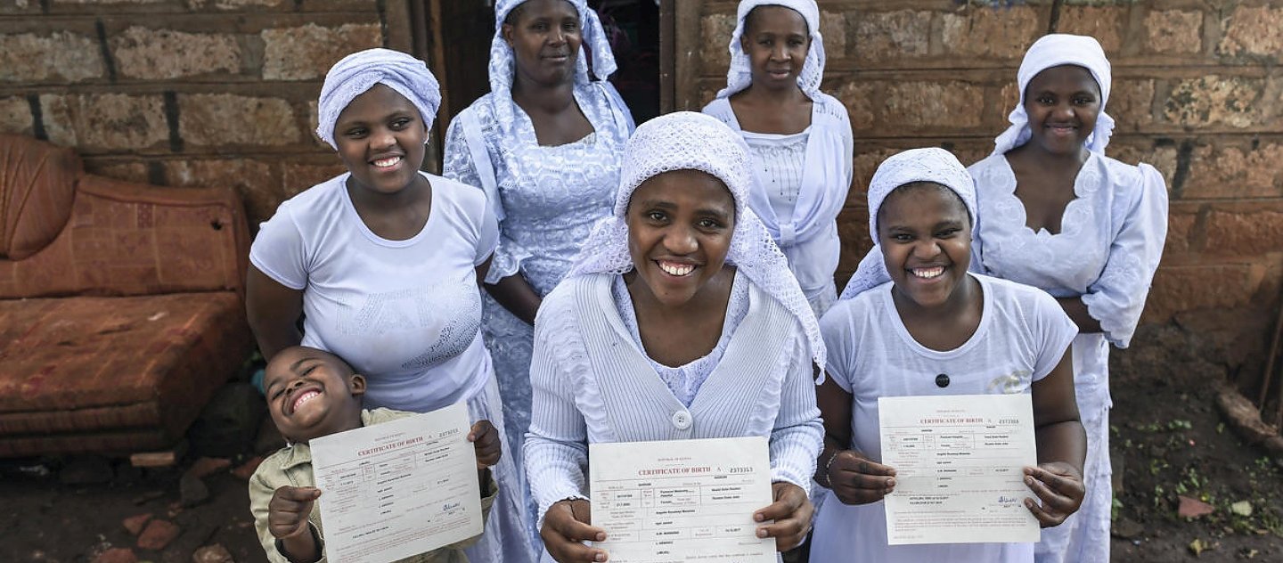 Nosizi Reuben (au premier plan), une femme apatride de la communauté Shona, pose avec sa famille alors qu'elle tient son certificat de naissance récemment délivré chez elle à Kinoo, au Kenya.