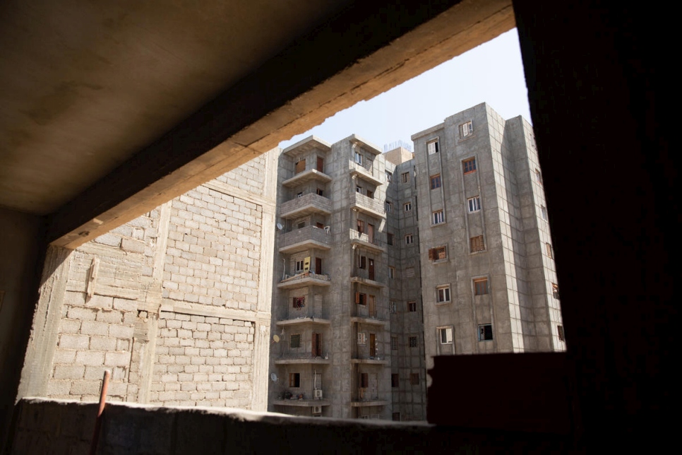 تطل النافذة في شقة حنان على مبانٍ أخرى غير مكتملة تستضيف حالياً أكثر من 100 عائلة ليبية نازحة.