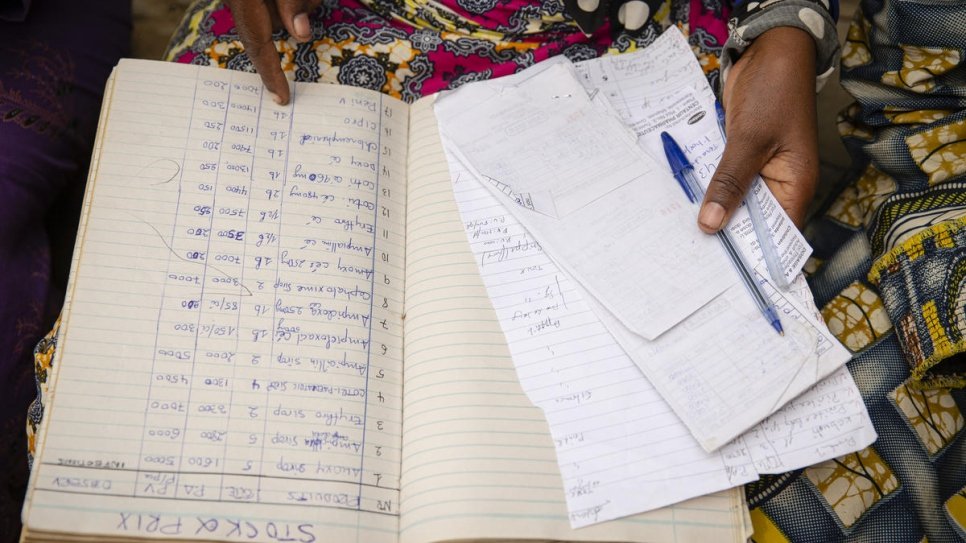One of the refugee women mentored by Sabuni Francoise Chikunda goes over the records of the women's group founded in Nakivale settlement, Uganda.