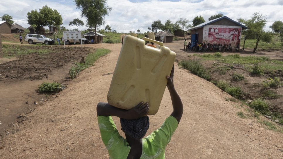 South Sudanese refugee Asha Rose Sillah carries a jerrycan of water from a water point to her home in Bidibidi refugee camp, Uganda.