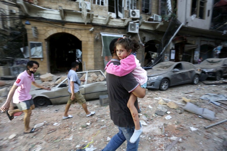Un homme transporte une enfant blessée vers un lieu sûr à la suite d'une explosion massive dans le port de Beyrouth, au Liban. 