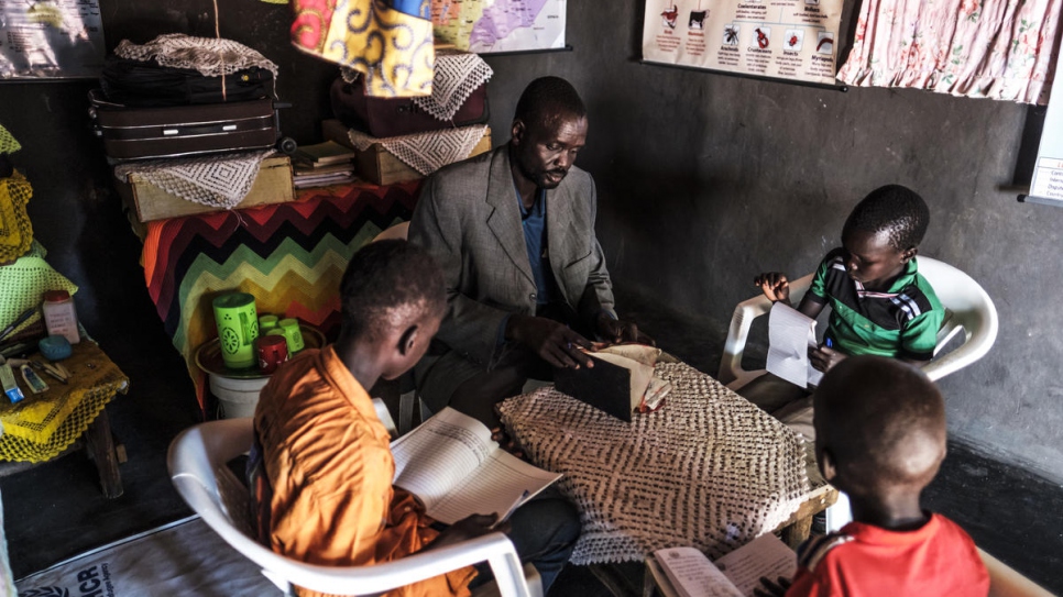 James Tut reads a book with his children at their home.