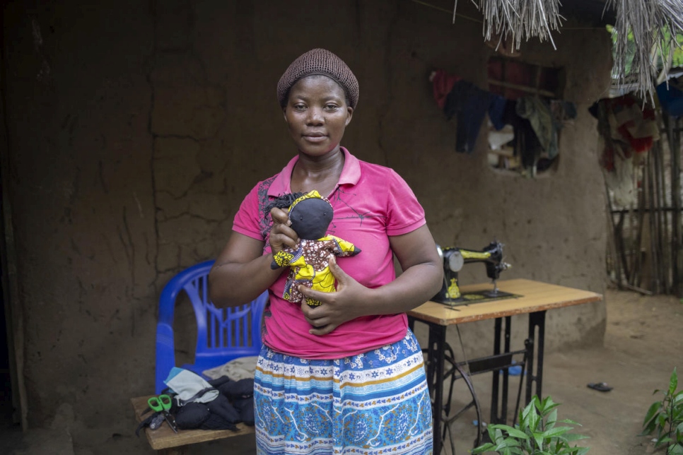 Kituza, a Congolese refugee, proudly shows off a doll she made at her home in Maratane refugee camp, northern Mozambique. 