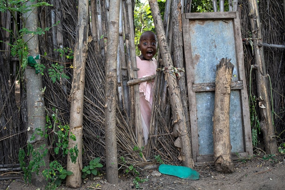 Surprised by the photographer, a young refugee girl peers through the fence of a garden in Maratane refugee camp, in northern Mozambique. 