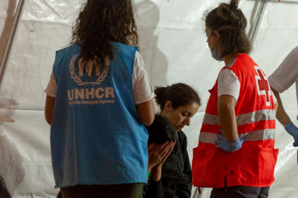 En Espagne, une employée du HCR porte assistance à des réfugiés et des migrants secourus en mer. 