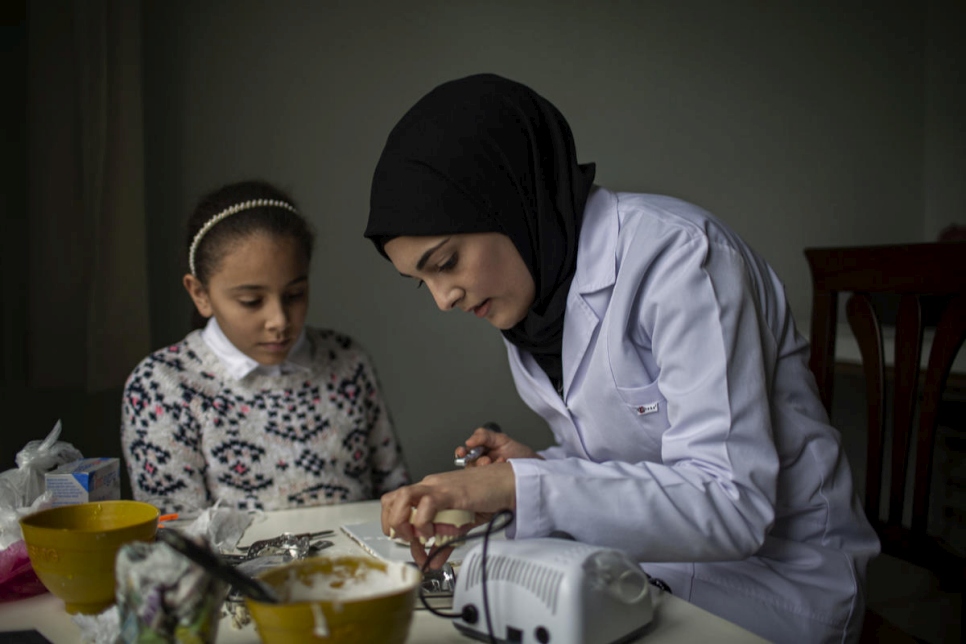 سيدرا تمارس مهاراتها في طب الأسنان في المنزل بينما تنظر إليها أختها الصغرى إسراء.