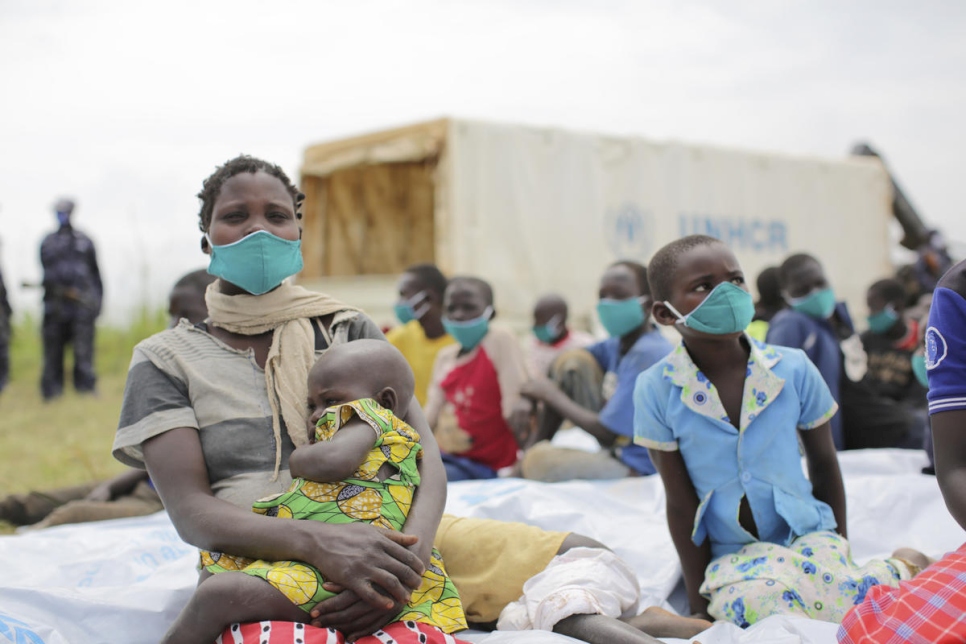 Anurith, une demandeuse d'asile de 29 ans originaire de la République démocratique du Congo, est assise avec ses enfants après avoir subi un examen médical près du poste frontière de Zombo, en Ouganda. 

