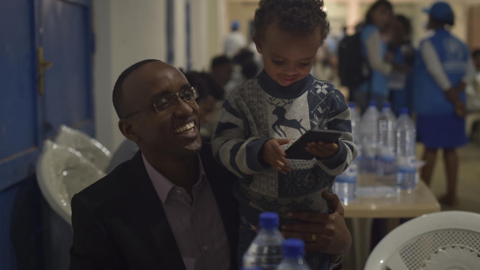 District Mayor Richard Mutabazi plays with a young child at the Gathora Emergency Transit Center, Rwanda.