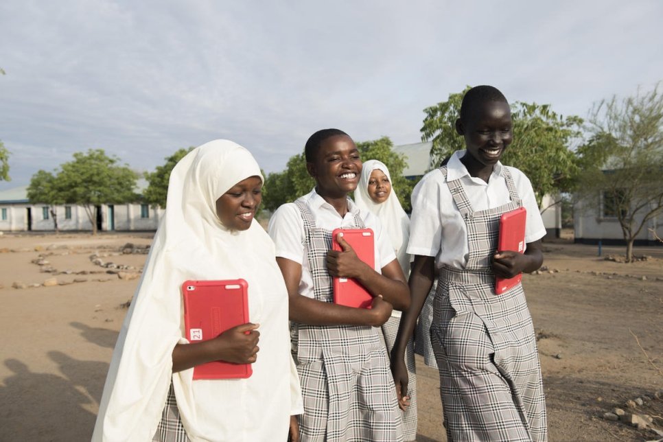 Kenya. Merinas, Mumina and Mary walk with their classmates and tablets through the school grounds