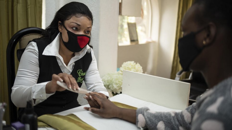 Congolese refugee Michelle, gives a customer a manicure at her beauty salon in Pretoria, South Africa. 