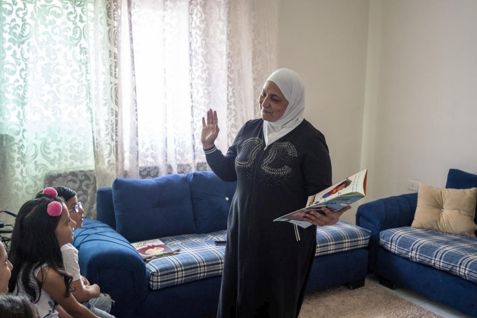 لطيفة اللحام، سفيرة برنامج "نحن نحب القراءة" تقرأ أمام مجموعة من الأطفال اللاجئين السوريين في شقة في عمان، الأردن.