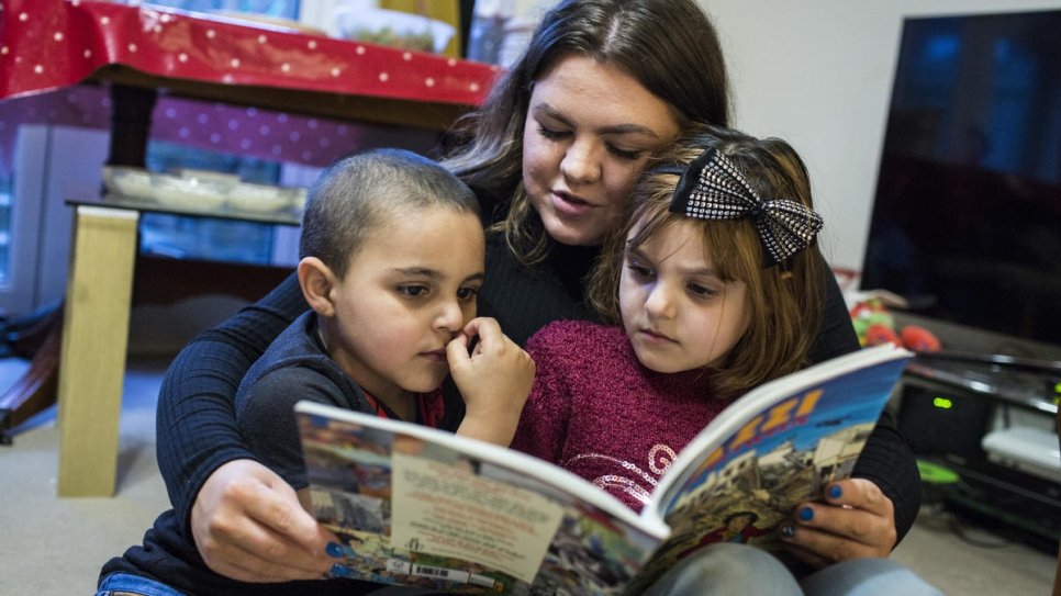 Amy Chapman reads with Adbul, 4, and Noor, 6, at the Arnout family home in Ottery St Mary, Devon, south-west England. Amy is a friend of the family and often drops by to help the children read English.