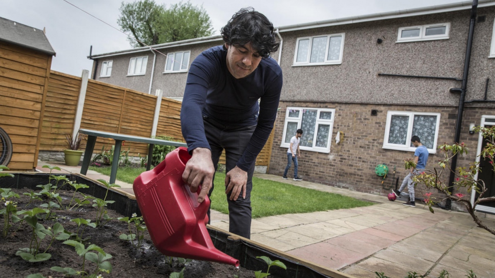 Sakkar Daour waters his strawberries putside his new home in Bury, north-west England.