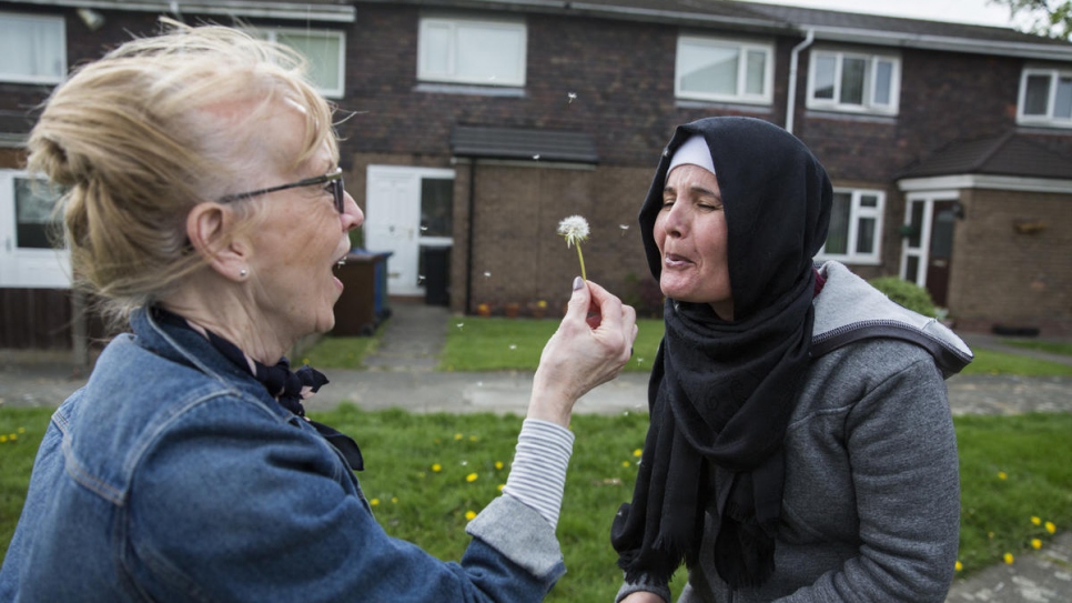 "I feel so proud of them. The boys are so confident, so warm towards us."

Colette Pritchard holds up a dandelion for Noura Daour, in Bury, Greater Manchester, north-west England. Colette, a retired banker, helps out as a driver when the family has appointments across town.
