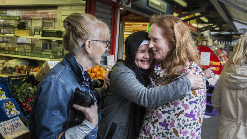 "The other day, one of our members was asked 'How's our family?' when going through the checkout till."

Noura Daour, 44, hugs Felicity Brangan during a trip to the market in Bury, north-west England with fellow community support volunteer, Colette Pritchard (left).