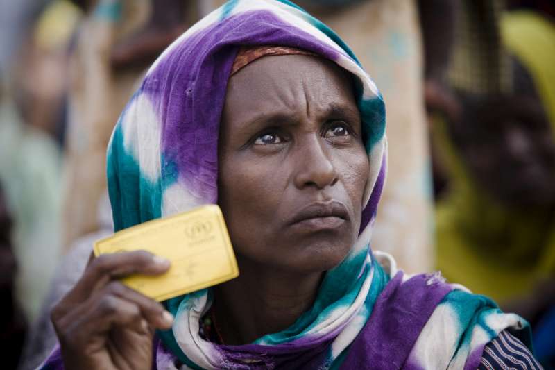 An internally displaced Somali woman, holding her registration card, waits for humanitarian supplies flown to Mogadishu 