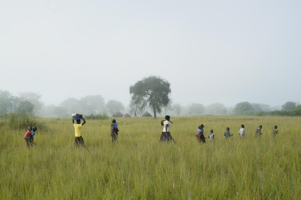 أطفال كوين يساعدونها في الأرض الواقعة في مخيم أوليجي، حيث تزرع الأرز. 
