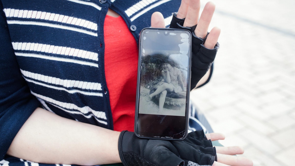 Tetiana Baransova, lauréate régionale pour l'Europe de la distinction Nansen pour les réfugiés, sur la place Sophia, à Kiev. Elle montre une photo d'elle à l'âge de 10 ans, la veille d'un accident après lequel elle se déplace désormais en fauteuil roulant. 