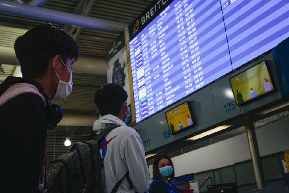 Dos menores no acompañados miran la pantalla de salidas en el aeropuerto de Atenas antes de tomar un vuelo a Luxemburgo fletado en el marco de una nueva iniciativa de reubicación de la UE.