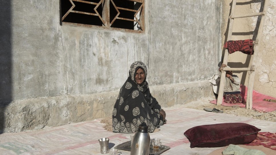 Sardar Bibi, 45 ans, prend le thé devant son nouveau logement dans la province de Kandahar, le 4 février 2020. 